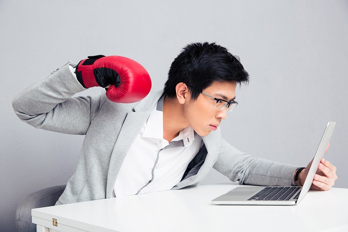 Businessman in boxing gloves reading to hit laptop